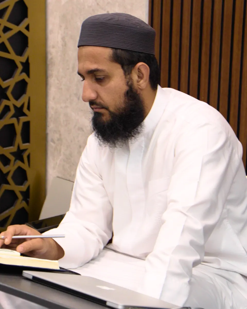A teacher in a white thobe preparing lessons at his desk